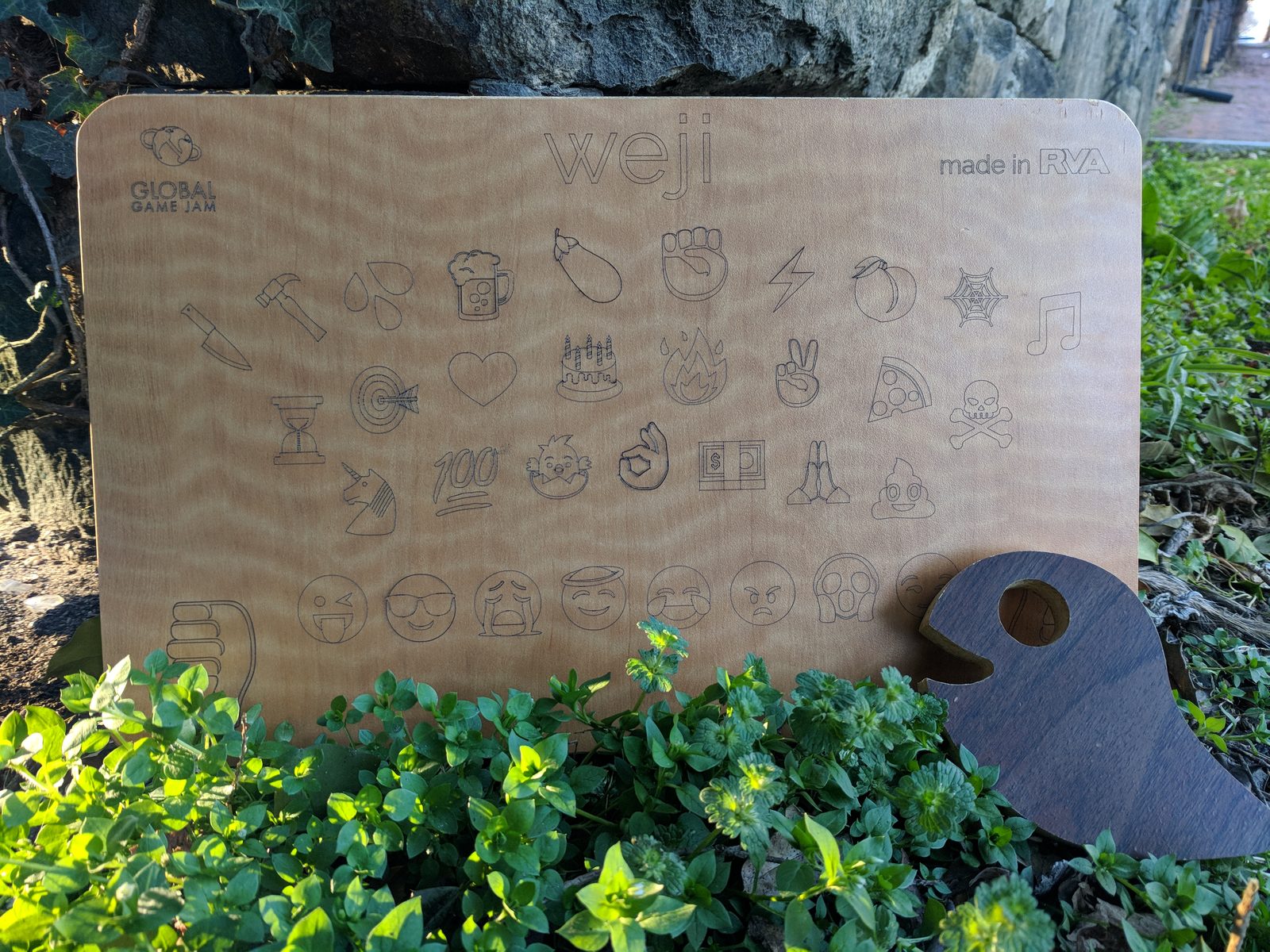 The full laser-cut Weji board and walnut planchette leaning against a stone wall in the greenery